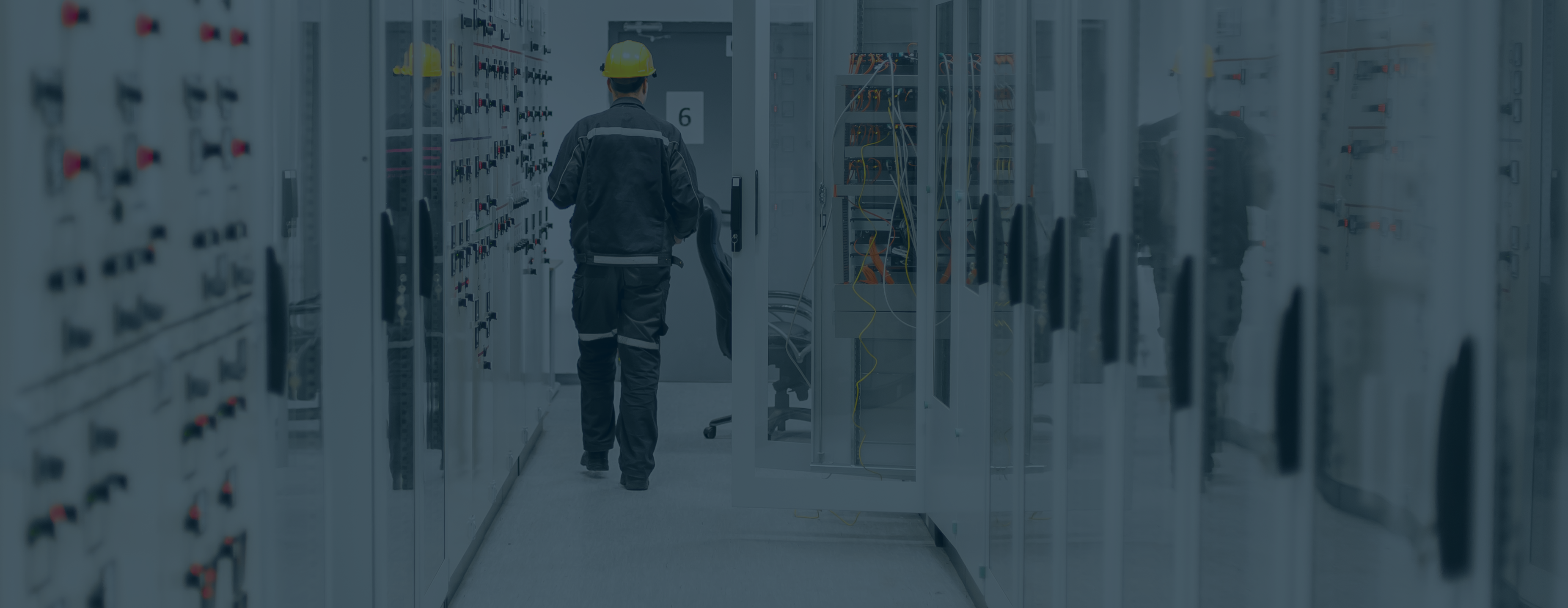 Medium voltage switchgear equipment with man in protective gear walking in background